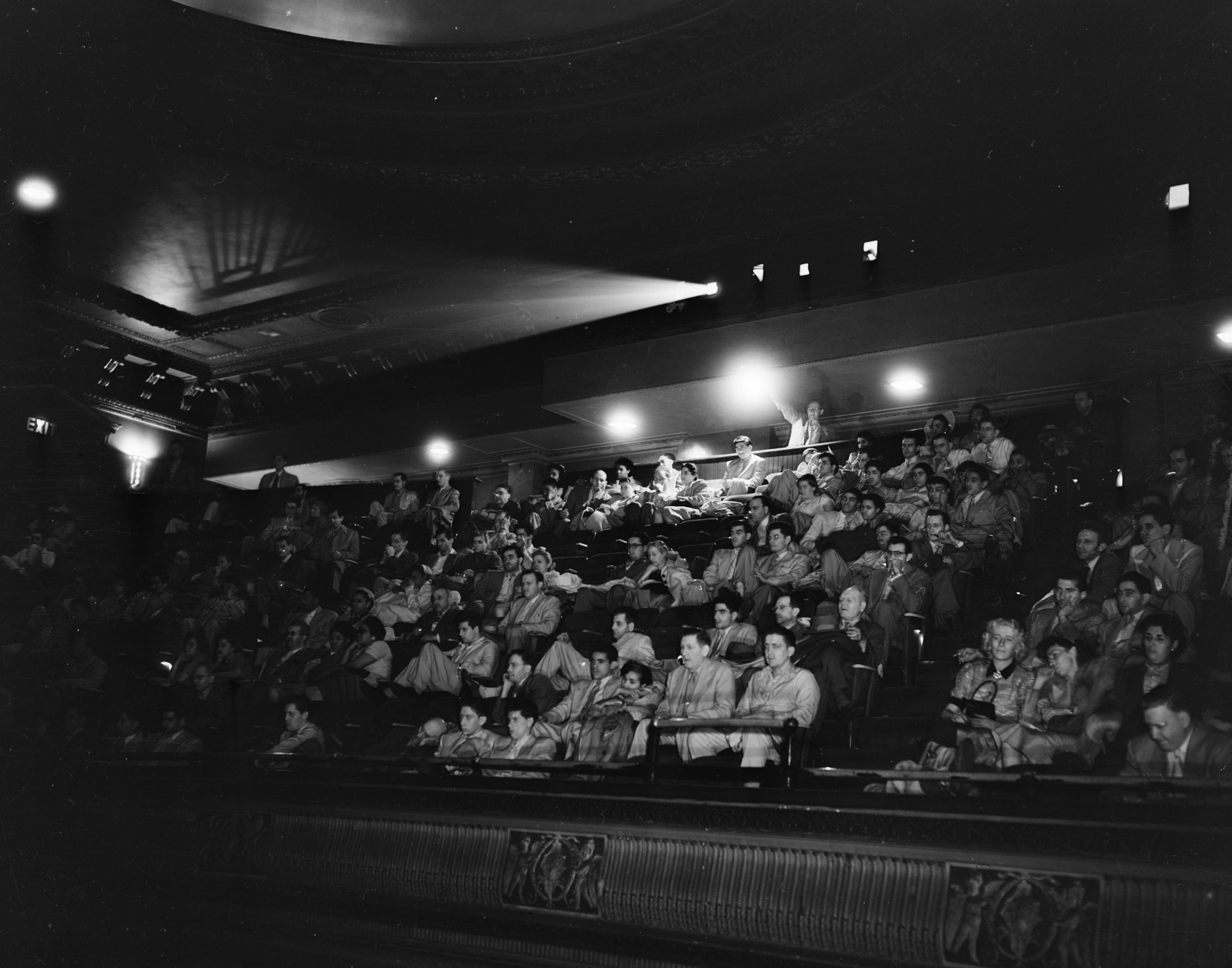 Một chùm tia chiếu xuyên qua bóng tối của nội thất một rạp chiếu phim thập niên 1940