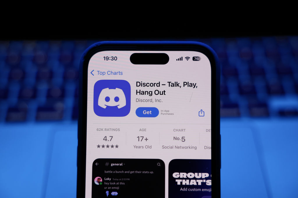 A laptop keyboard and Discord on the App Store are displayed on a phone screen on March 17, 2025.